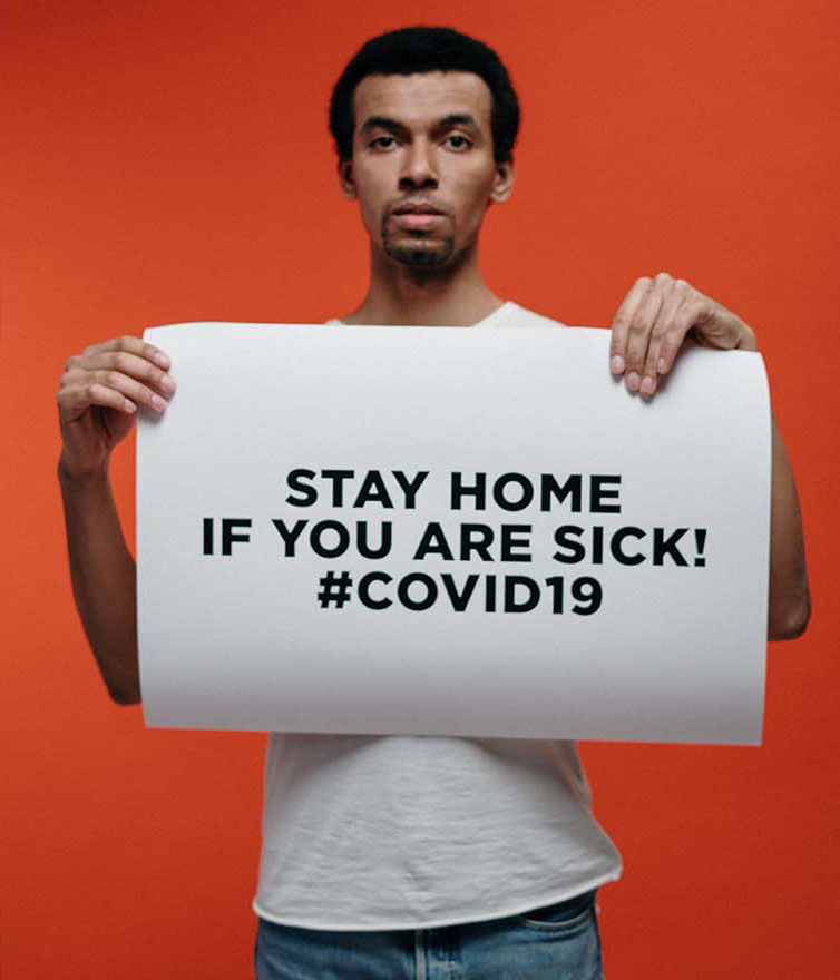 Man holding sign reading Stay Home if You are Sick with #Covid19